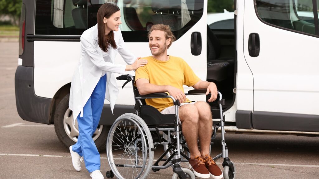 Arzt und ein im Rollstuhl sitzender Mann in der Nähe eines Krankentransportwagens im Freien