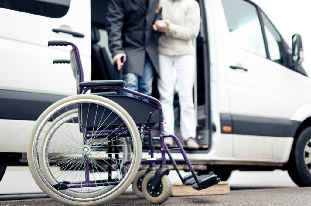 Krankenschwester unterstützt älteren Herrn beim Aussteigen aus einem Van